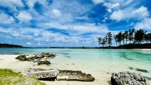 Aqua blue water of Vanuatu's Eton Beach with powdery white sand beach littered with the occasional coral boulder.