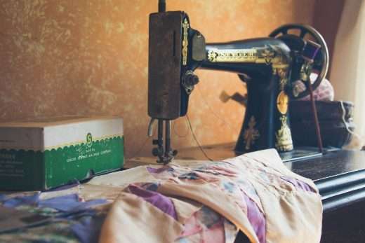 Classic Singer sewing machine in black and gold with a piece of light pink fabric in mid-tailoring